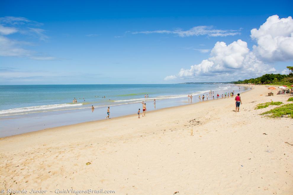 Imagem de turistas nas areias claras da Praia de Taperapuan.